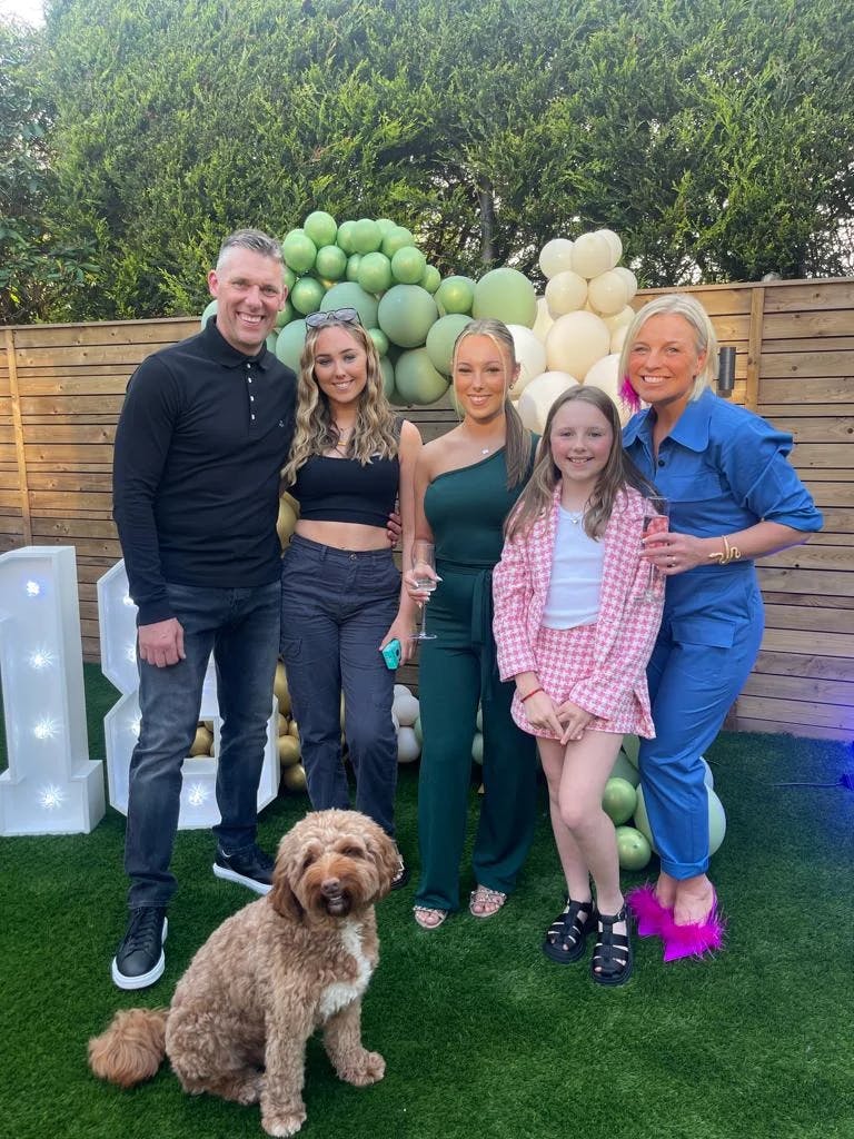 An image portraying Louby Lou the kids’ party entertainer and her family - her husband, three daughters and family pet dog in the garden at her daughter’s home birthday party. 