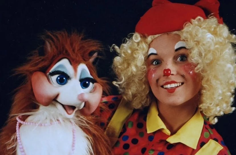 This is an image showing Louby Lou the Children’s Entertainer in her clown attire holding a large animal puppet.